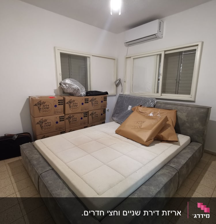 חדר שינה עם קופסאות קרטון ומיטה אפורה